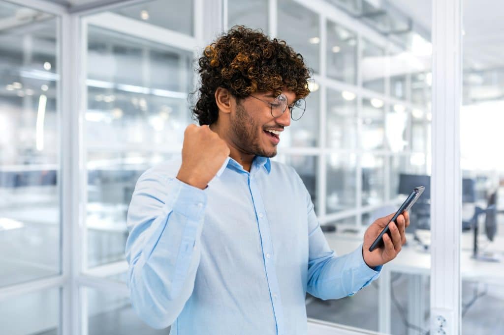 Successful hispanic programmer inside office and celebrating victory and successful achievement