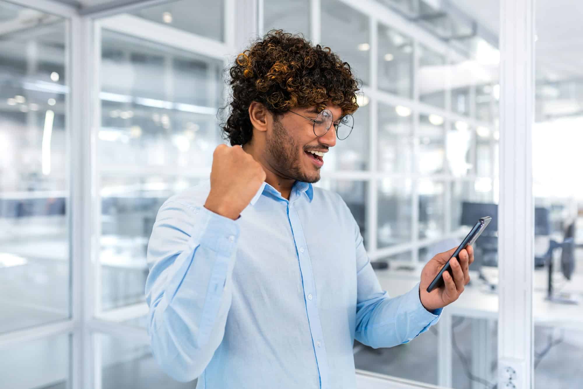 Successful hispanic programmer inside office and celebrating victory and successful achievement